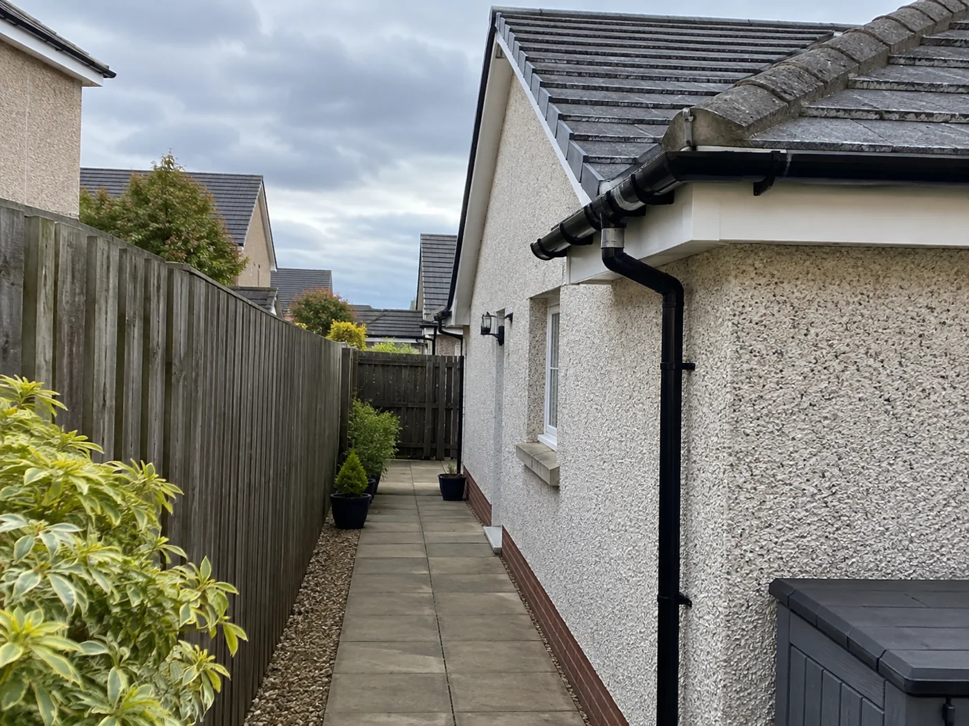 Paved side path beside a house with roof eaves above